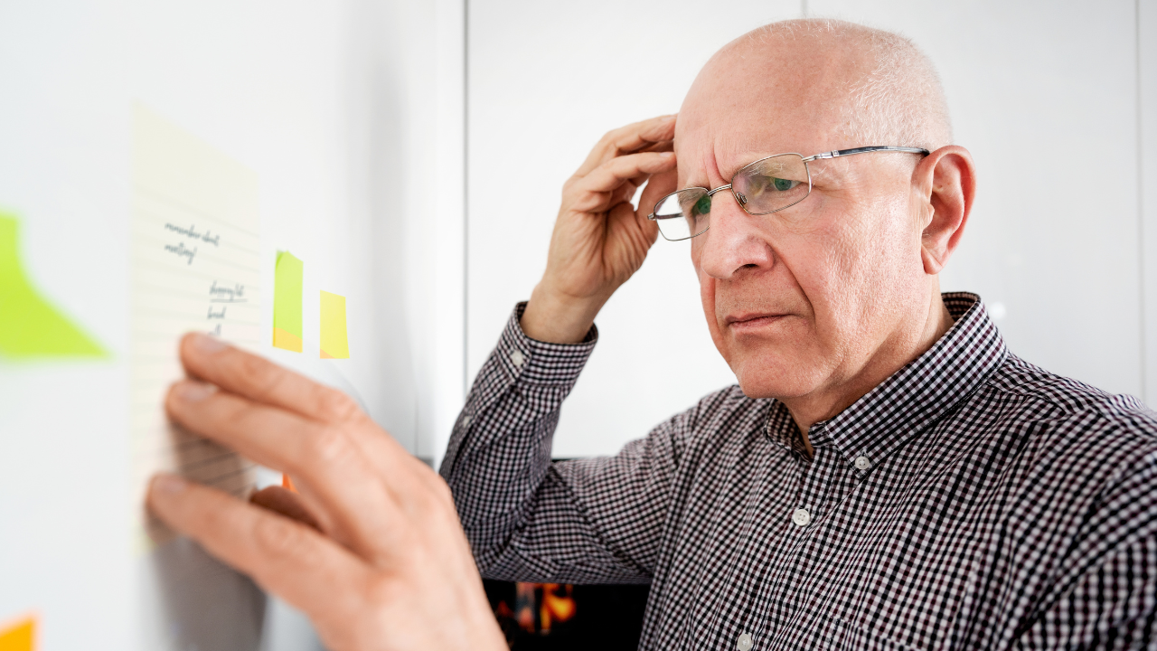 Senior man looking concerned and confused at notes on a board, showing memory loss as one of the 12 Signs It Might Be Time For Assisted Living.