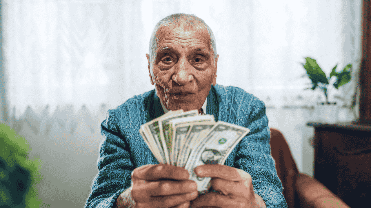 Elderly man holding cash, symbolizing the high costs and question of why are assisted living facilities so expensive.