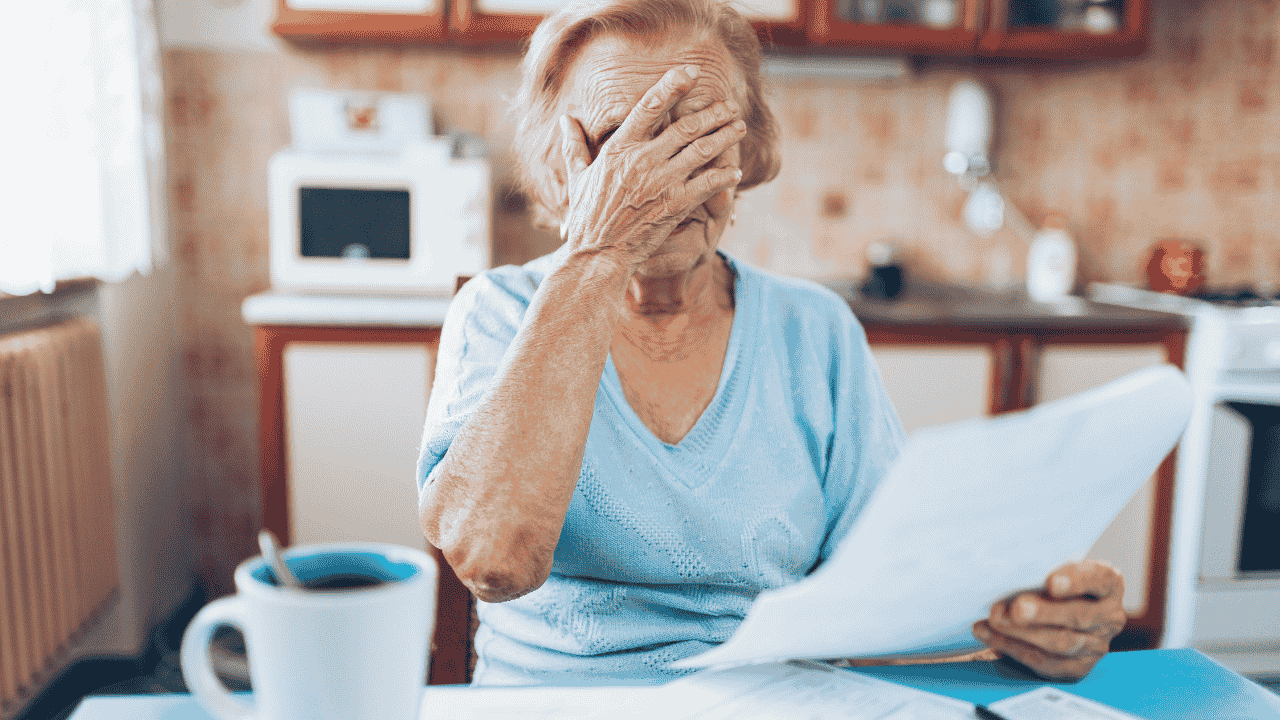Elderly woman stressed while reviewing bills at home, reflecting financial concerns and the question “is elderly tax deductible.”
