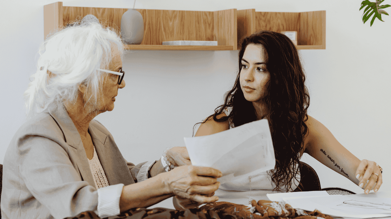 A senior woman reviews documents with a younger caregiver, illustrating the tax credit for taking care of elderly parent.
